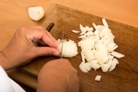 Cutting and chopping an onion on a wooden board with a knife