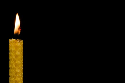 Candle made of beeswax,hand-rolled candle against a black background