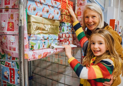 Little girl and her grandmother are donating a Christmas charity box in their local supermarket.