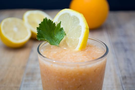 Fresh lemonade with ginger decorated with green celery leaves and lemon on the dark background