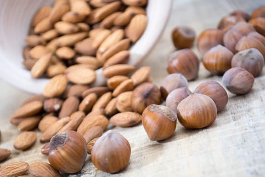 Spilled almonds and hazelnuts out of the bowl on the table