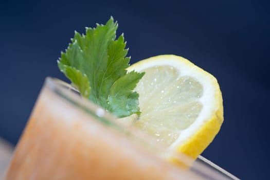 Fresh lemonade with ginger decorated with green celery leaves and lemon on the dark background