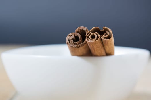 Close up of cinnamon sticks in a white bowl shot with shallow depth of field
