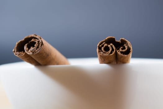 Close up of cinnamon sticks in a white bowl shot with shallow depth of field