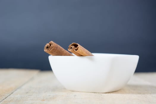 Close up of cinnamon sticks in a white bowl shot with shallow depth of field