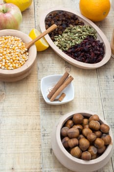 Wooden table with dry fruits and various seeds, cinnamon and other ingredients for healthy meal