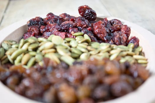 Bowl full with dry fruits and pumpkin seeds on the wooden table, shoot with selective focus