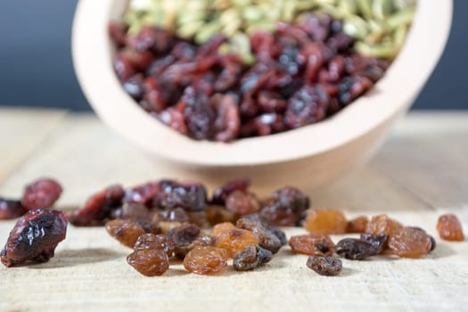 Bowl full with dry fruits and pumpkin seeds on the wooden table, shoot with selective focus