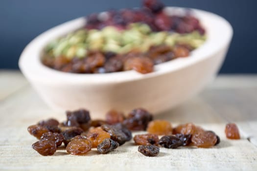 Bowl full with dry fruits and pumpkin seeds on the wooden table, shoot with selective focus