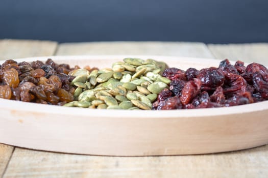 Bowl full with dry fruits and pumpkin seeds on the wooden table, shoot with selective focus