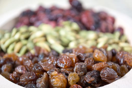 Bowl full with dry fruits and pumpkin seeds on the wooden table, shoot with selective focus