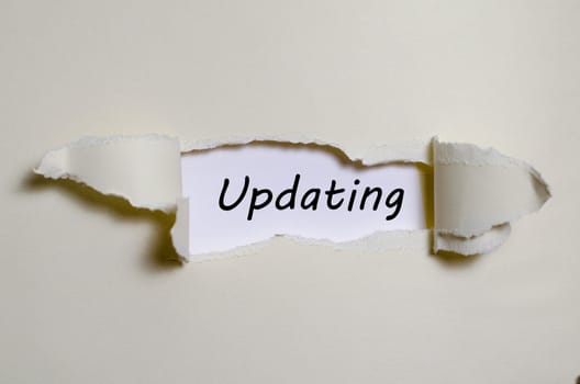 The word updating appearing behind torn paper