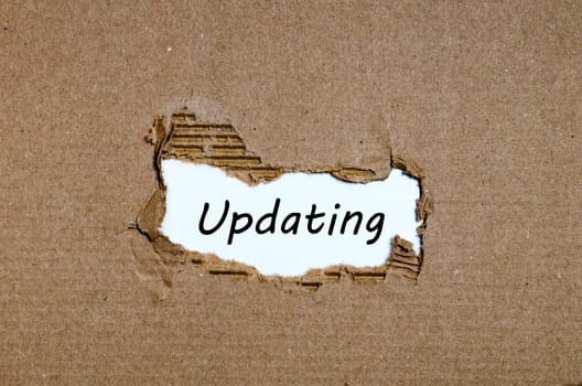 The word updating appearing behind torn paper