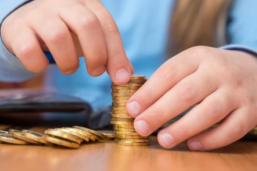 Child collects a stack of golden coins, close-up