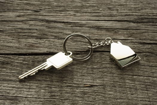 Key with keychain house on a wooden board