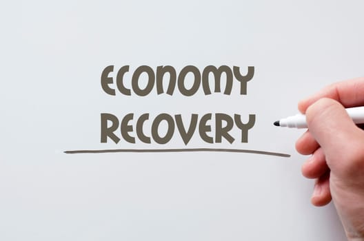 Human hand writing economy recovery on whiteboard