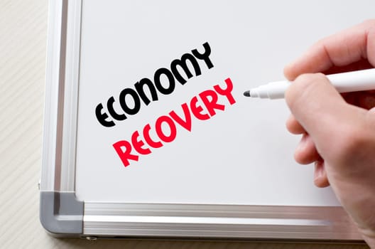 Human hand writing economy recovery on whiteboard