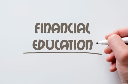 Human hand writing financial education on whiteboard