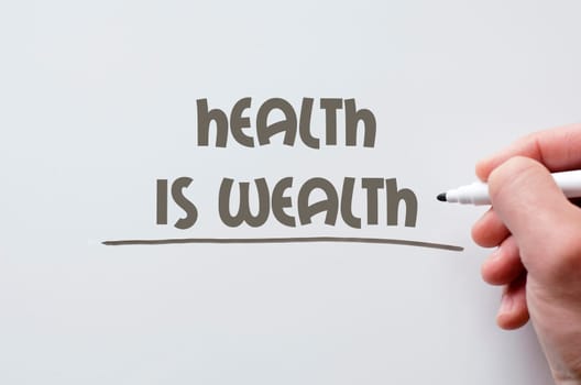 Human hand writing health is wealth on whiteboard