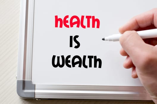 Human hand writing health is wealth on whiteboard