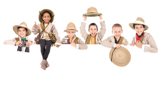 Children's group with safari clothes and gear over a white board