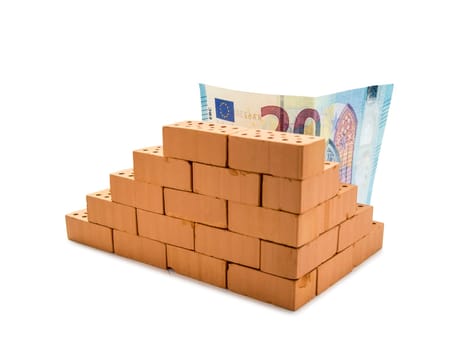 indicated masonry of toy bricks with a 20 euro banknote behind it on a white background