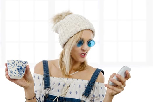 beautiful blond woman with a cup of tea and phone, isolated on white background