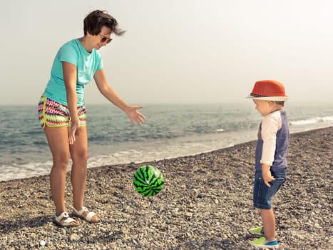 Mother and son playing ball near the sea