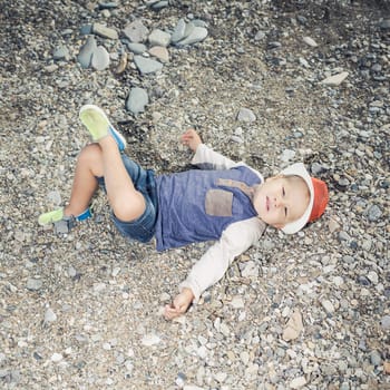 Fashion boy relaxing on a pebble beach