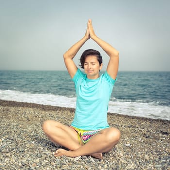 Woman meditating at seaside. Foggy weather