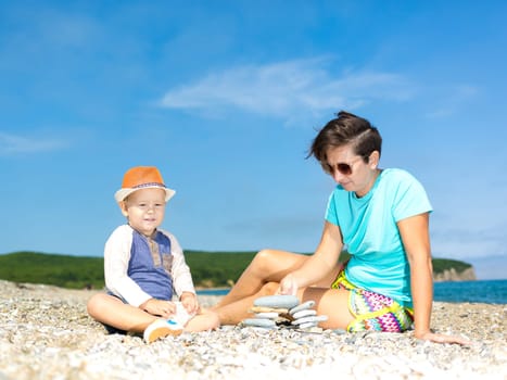 Mother and son making pebble stack near the sea