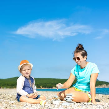 Mother and son making pebble stack near the sea