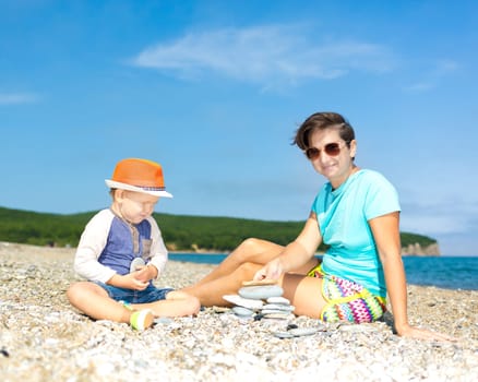 Mother and son making pebble stack near the sea