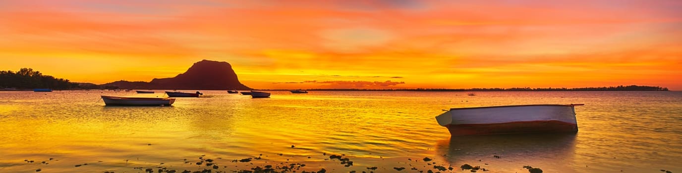 Fishing boat at sunset time. Le Morn Brabant on background. Mauritius. Panorama