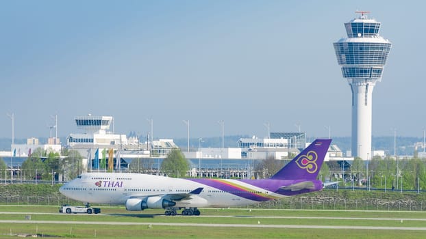 Munich, Germany - May 6, 2016: Jet airliner Boeing 747-400 of Thai Airways International airlines taxiing on pushback tug at Munich international passenger airport
