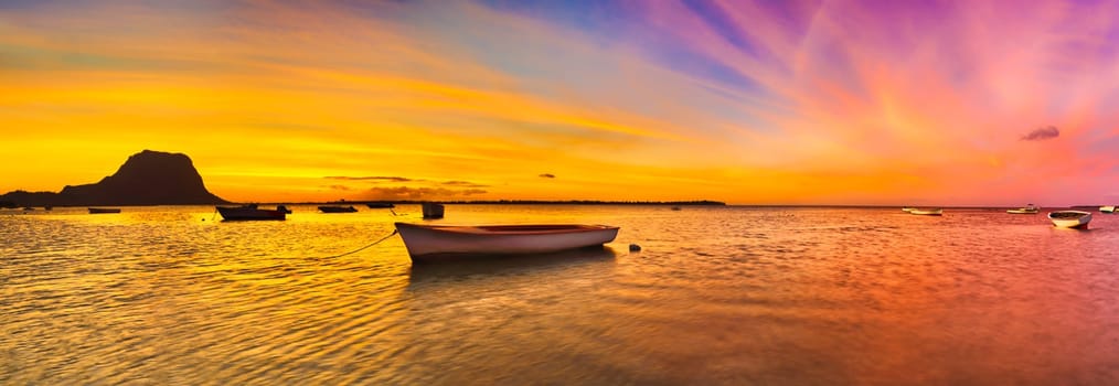 Fishing boat at sunset time. Le Morn Brabant on background. Mauritius. Panorama