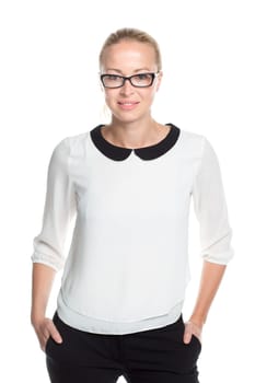 Portrait of beautiful smart young businesswoman wearin black eyeglasses, standing with arms in pockets against white background.