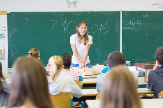 Instructor teaching first aid cardiopulmonary resuscitation course and use of automated external defibrillator workshop in primary school class.