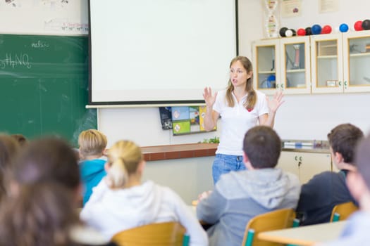 Instructor teaching first aid cardiopulmonary resuscitation course and use of automated external defibrillator workshop in primary school class.
