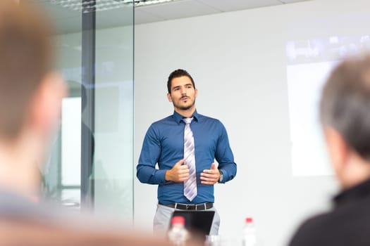 Businessman making a presentation at office. Business executive delivering a presentation to his colleagues during meeting or in-house business training, explaining new business concept and strategy.