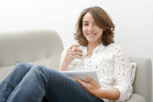 beautiful young woman with a tablet drinks a cup of tea