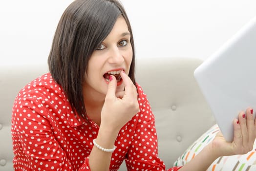 A young brunette eats chocolate on her sofa