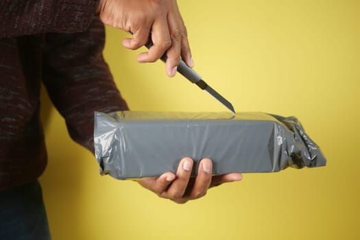 Hand reaches to slice open a wrapped package with a knife.