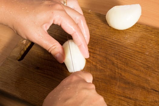 Cutting and chopping an onion on a wooden board with a knife