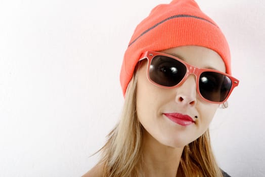 portrait of beautiful blond woman with winter hat and sunglasses on white