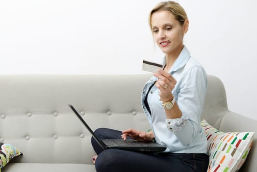 smiling woman shopping online with credit card and laptop.