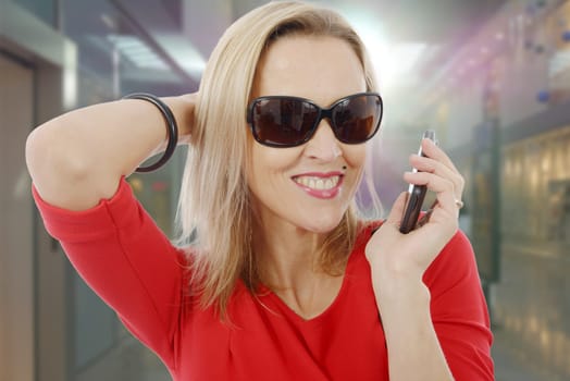 blond middle-aged businesswoman with phone and sunglasses on white
