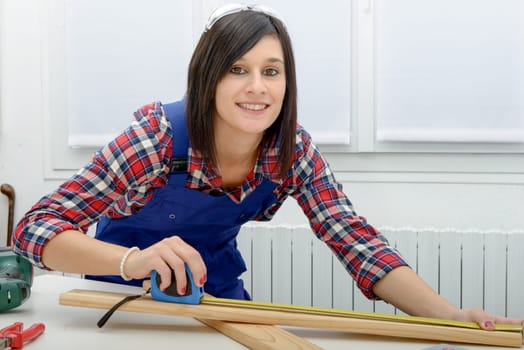 pretty young  woman builder measuring a plank of wood