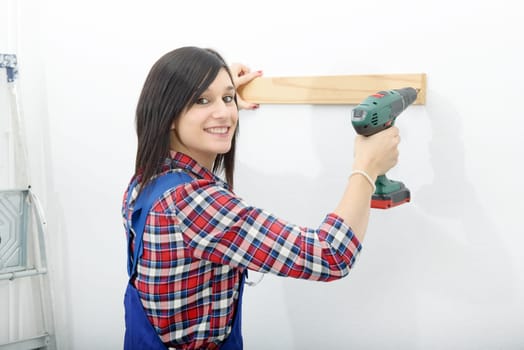 pretty young brunette woman holding cordless drill