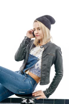 fashion young blonde woman with jeans overalls, talking on the phone